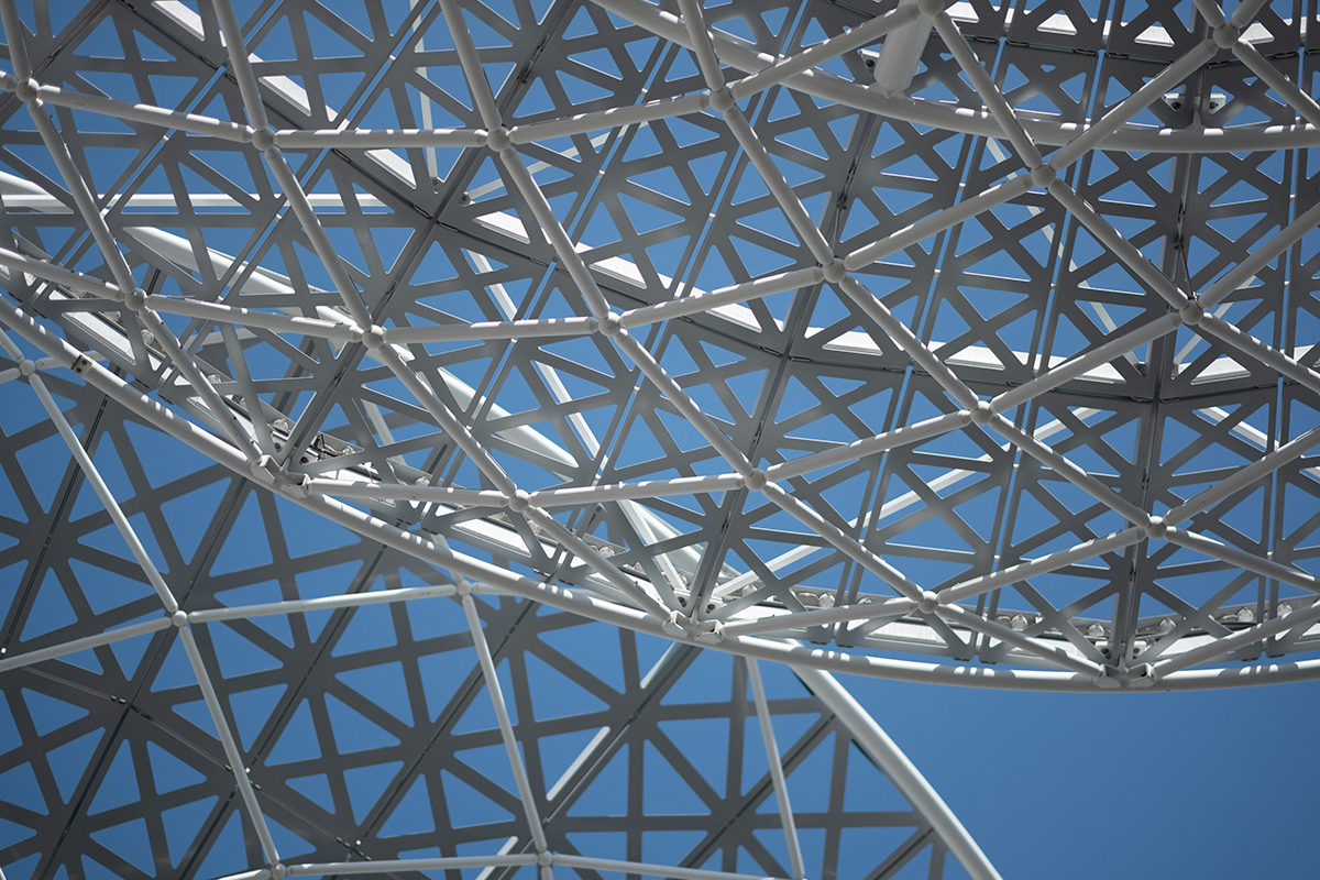 A geometric architectural lattice against a blue sky