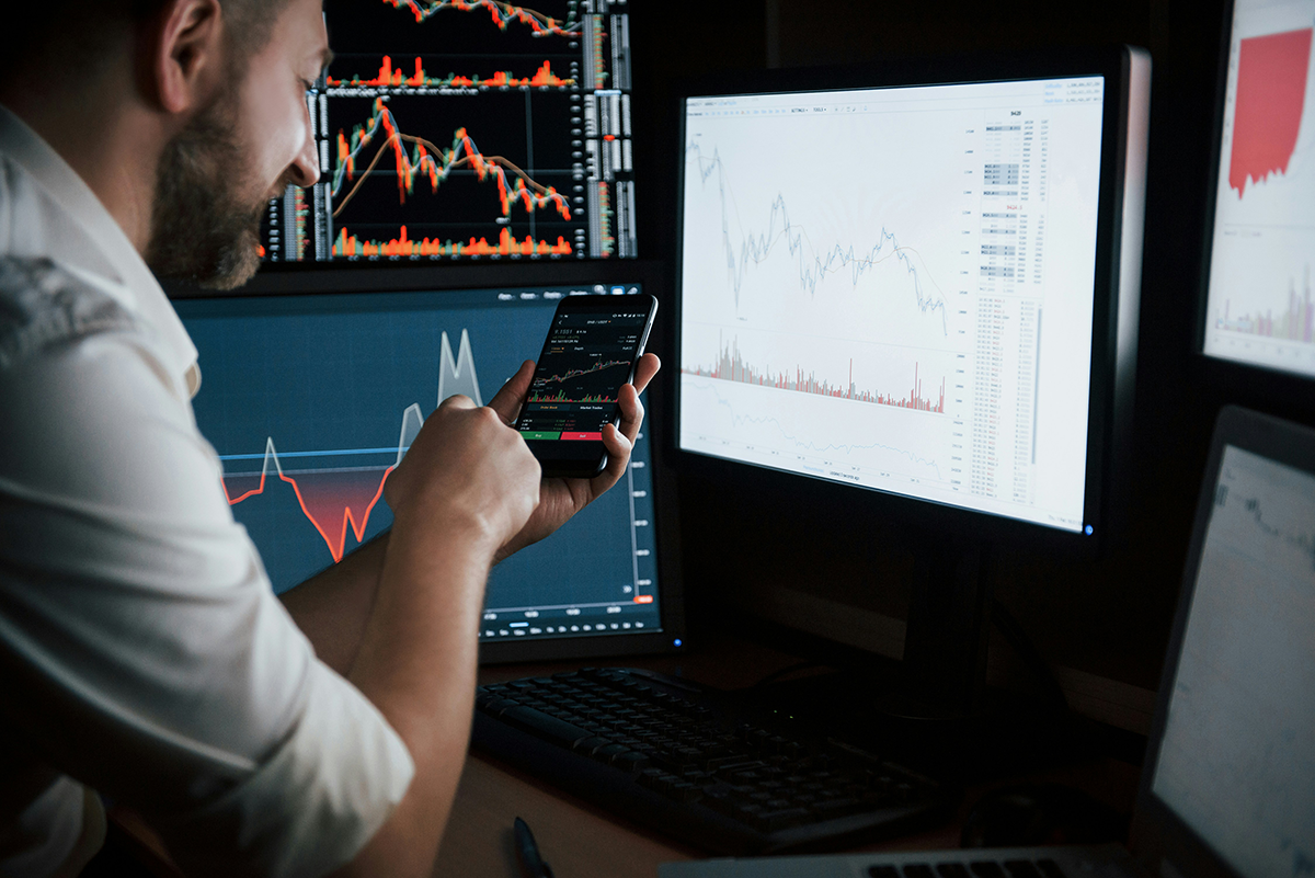 A trader analysing market charts across multiple screens