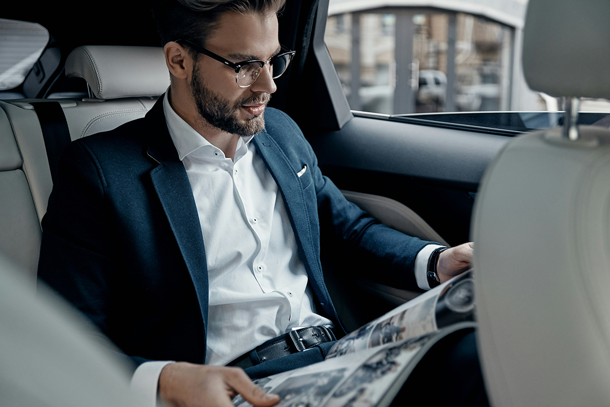 A businessman reading in the back of a car