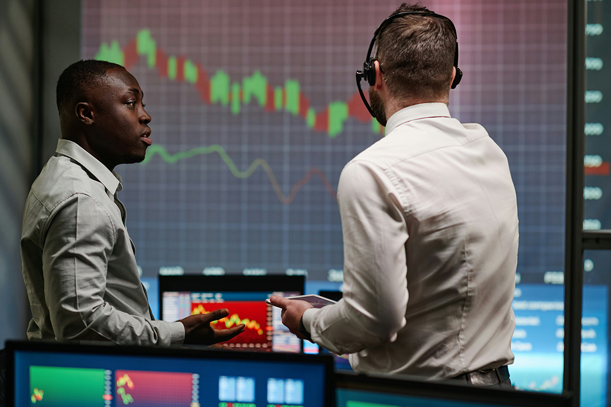 Two advisers reviewing market charts on a trading floor