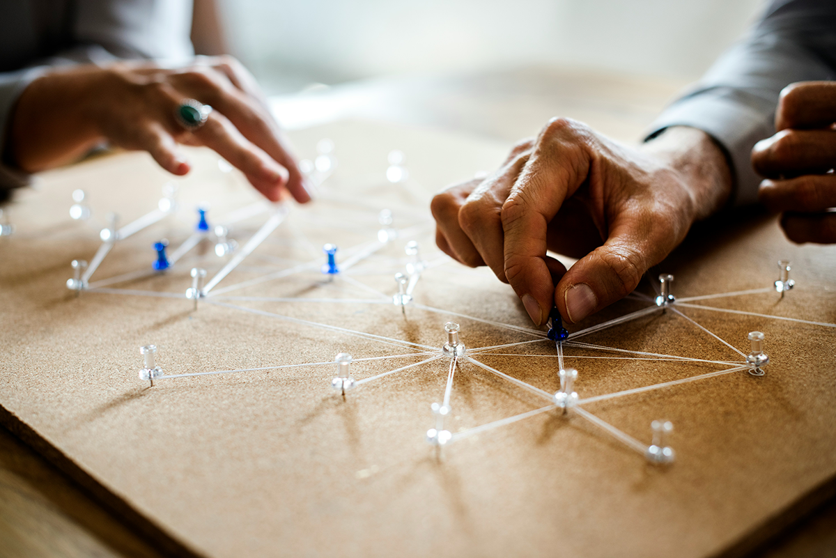 Two people connecting pins with string on a board